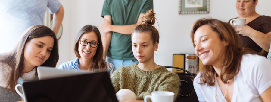 Wokół komputera zgromadzone są osoby uczestniczące w szkoleniu online